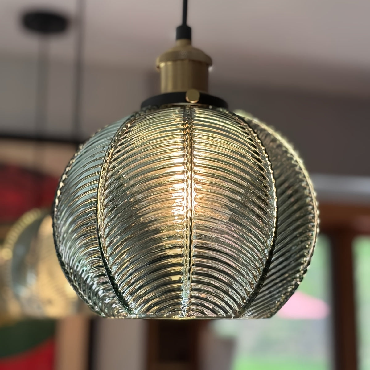 Suspension boule en verre vert aux nervures en éventail