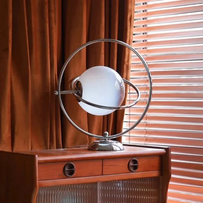 Lampe à poser globe de verre cerclé d'anneaux chromés, style Saturne