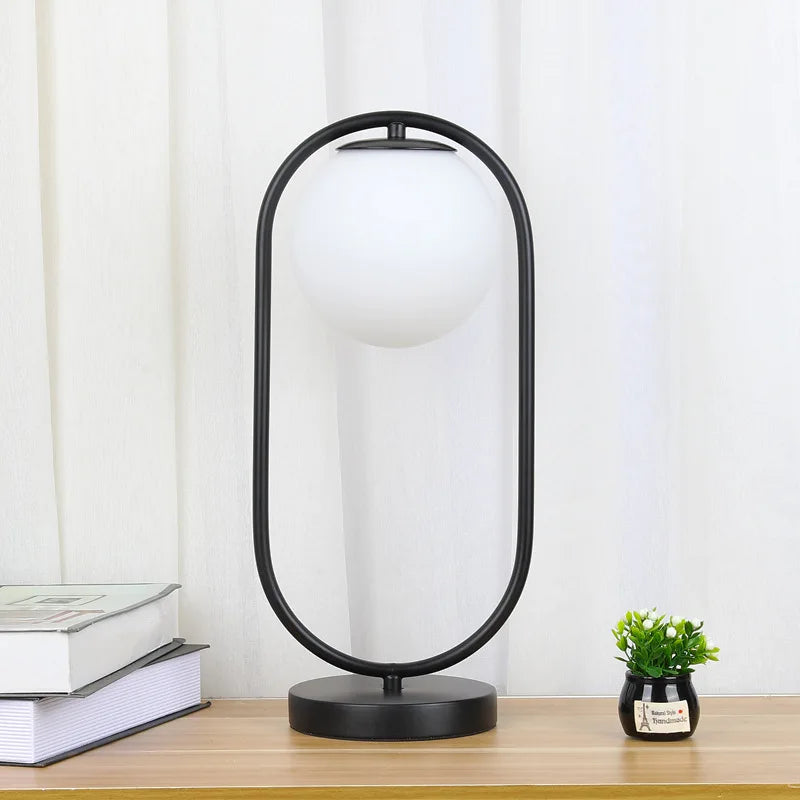 Lampe à poser globe en verre opalin dans un anneau doré ou noir