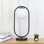 Lampe à poser globe en verre opalin dans un anneau doré ou noir