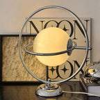 Lampe à poser globe de verre cerclé d'anneaux chromés, style Saturne