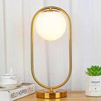 Lampe à poser globe en verre opalin dans un anneau doré ou noir
