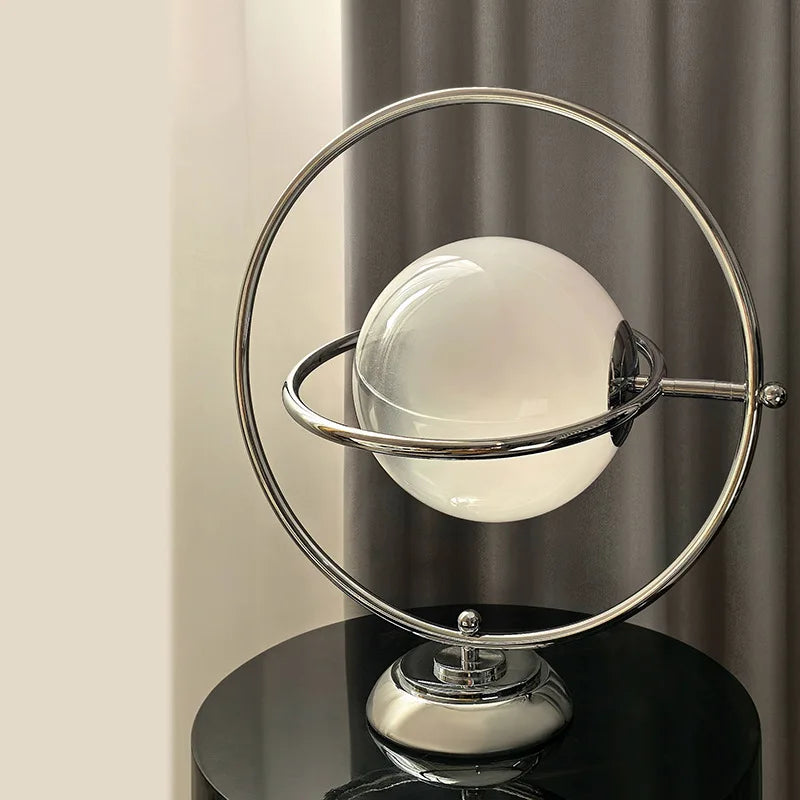 Lampe à poser globe de verre cerclé d'anneaux chromés, style Saturne