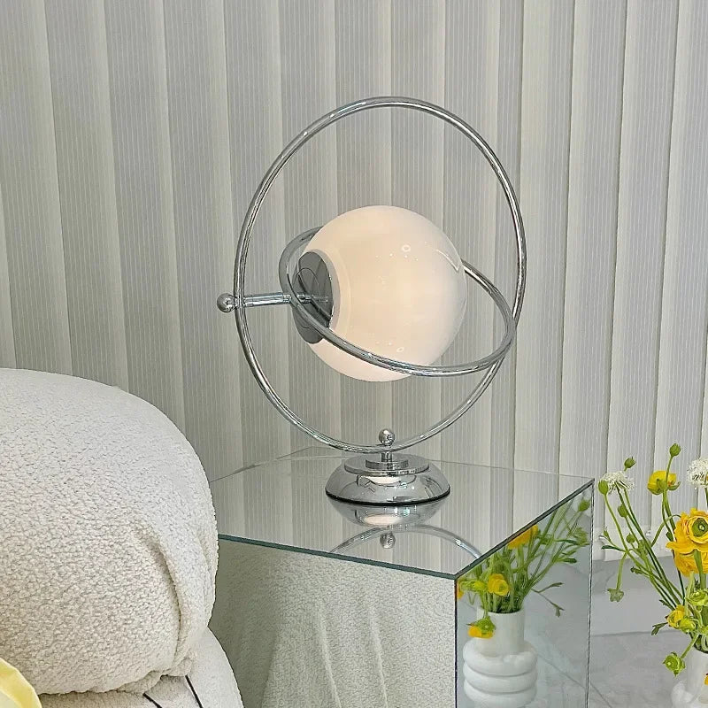 Lampe à poser globe de verre cerclé d'anneaux chromés, style Saturne